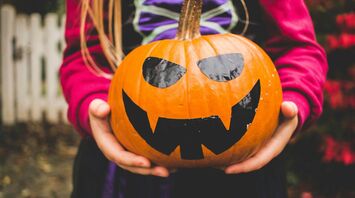 Child holding a Halloween pumpkin
